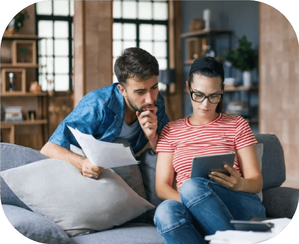 Image d'un couple sur son canapé entrain de calculer les aides disponibles pour son projet de rénovation globale/d'ampleur avec les aides de l'état