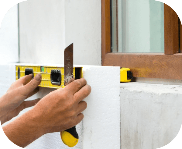 Photo d'un ouvrier entrain de faire des découpes sur une plaque de polystyrène pour réaliser l'isolation extérieure des murs d'une maison